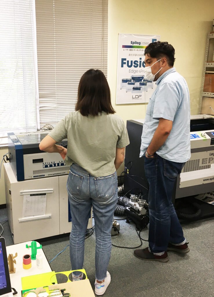 ▲ハイメ教授とU-suke（FDAプロデュサー）の指導を受けながらレーザー加工機で試作品制作。