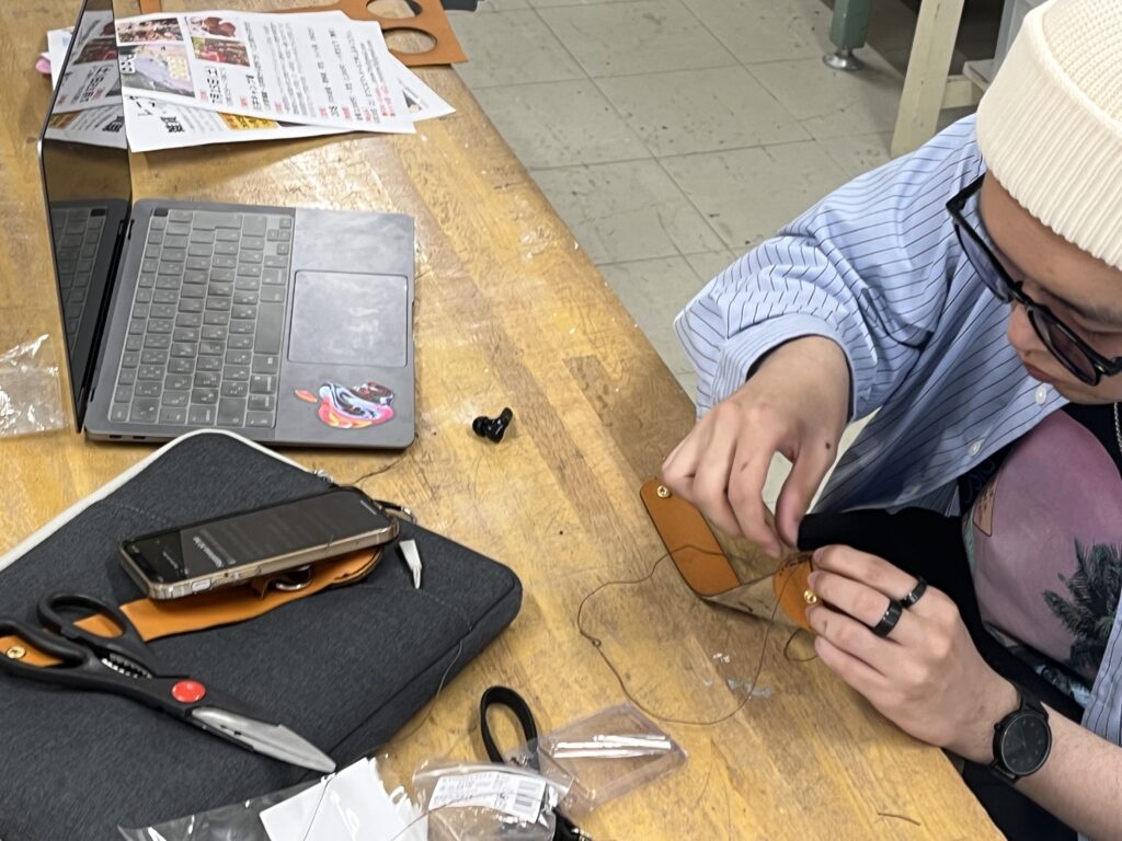 レーザー加工機でカットした革を専用の針と糸で裁縫する学生。