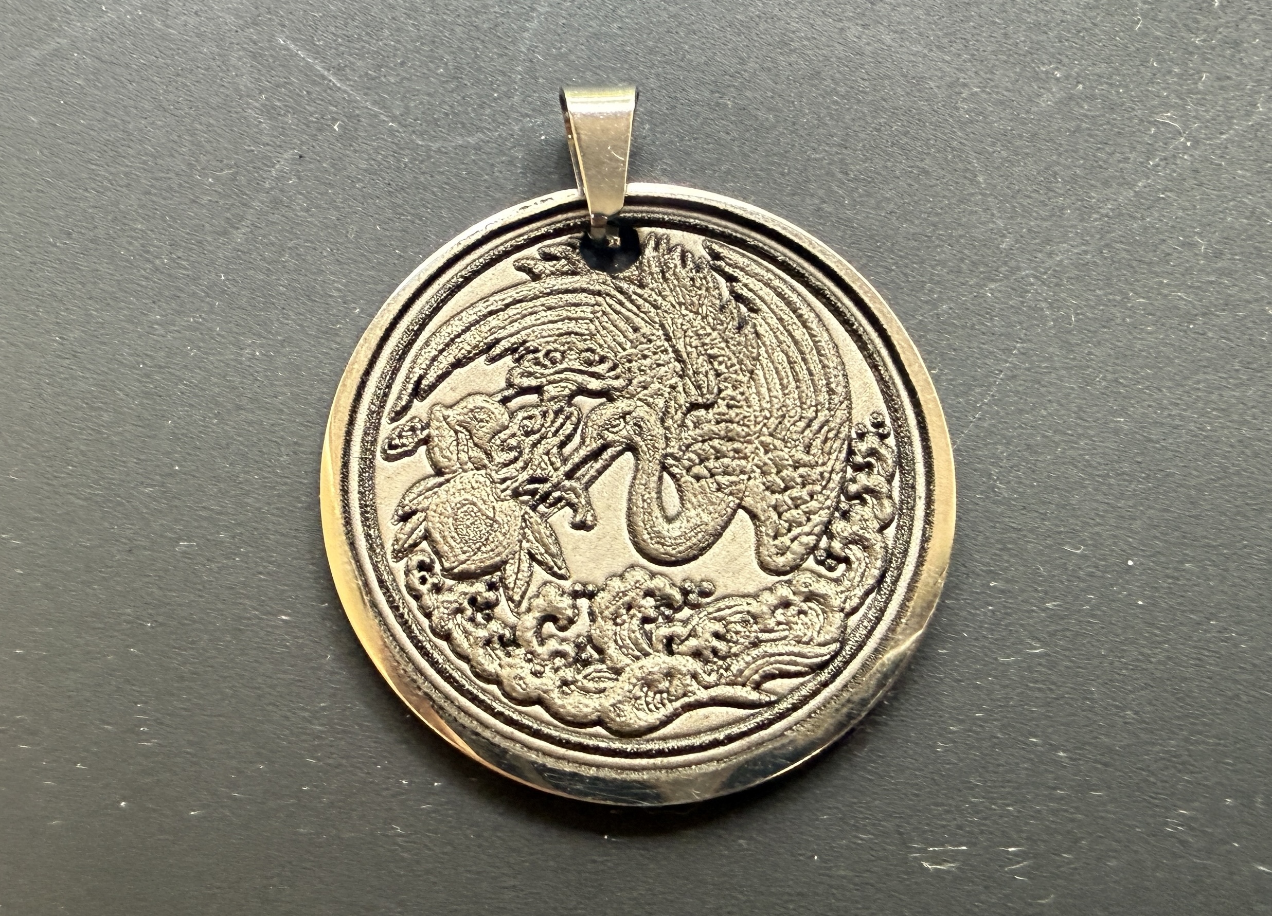 円の形にカットされた金属板に龍を彫ったもの